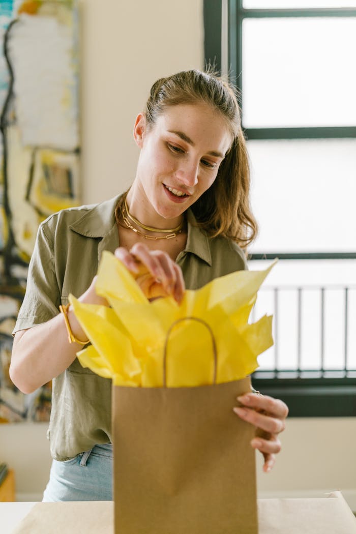 Mastering the First Impression: Your intriguing post title goes here Adult woman showcasing her craft business skills by packing a gift with yellow tissue paper.